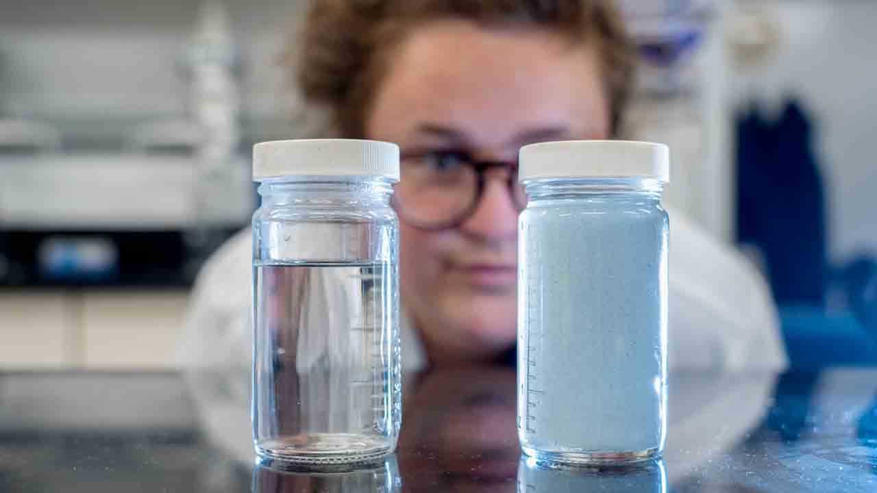 Water Quality Lab specialist examines two containers holding water samples
