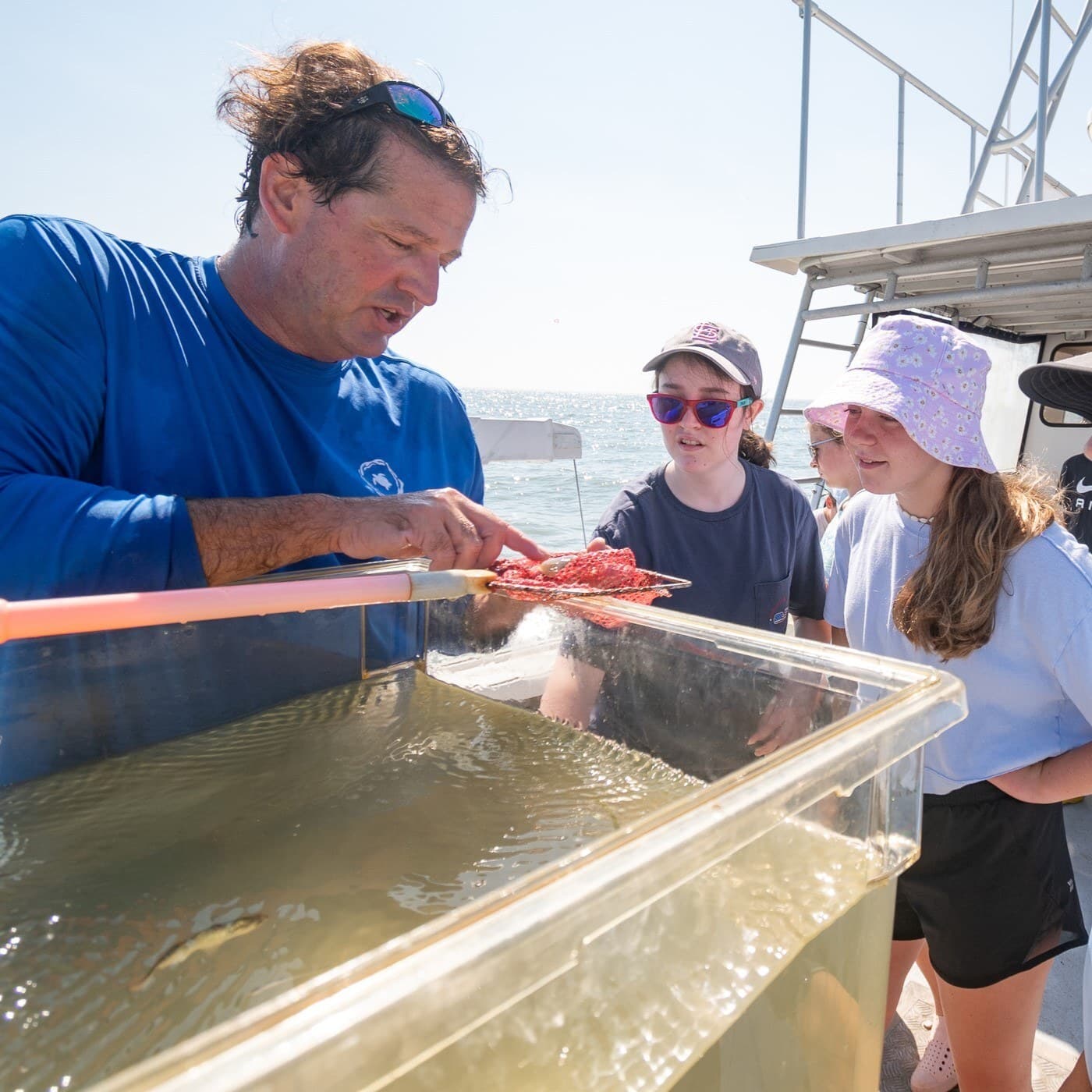 Aquarium educator on boat shows fish to summer campers