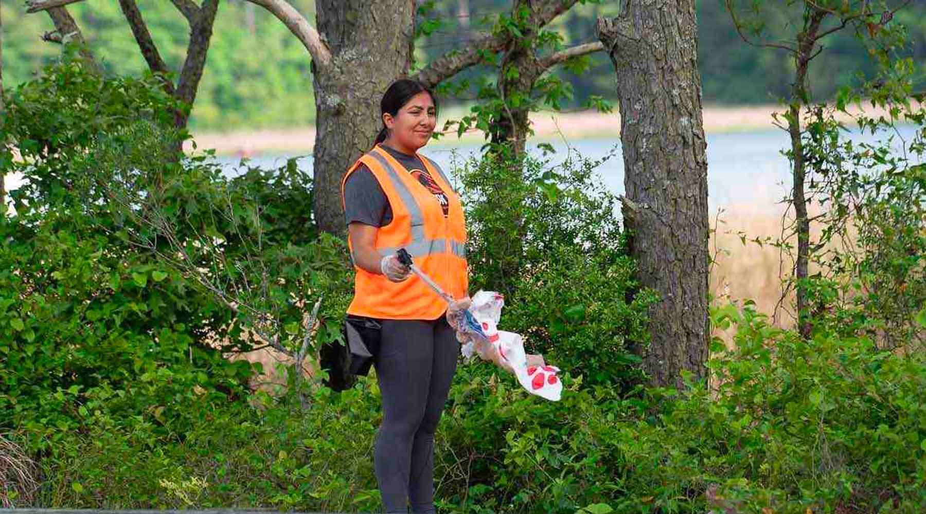 Woman in Orange Vest Picking Up Trash