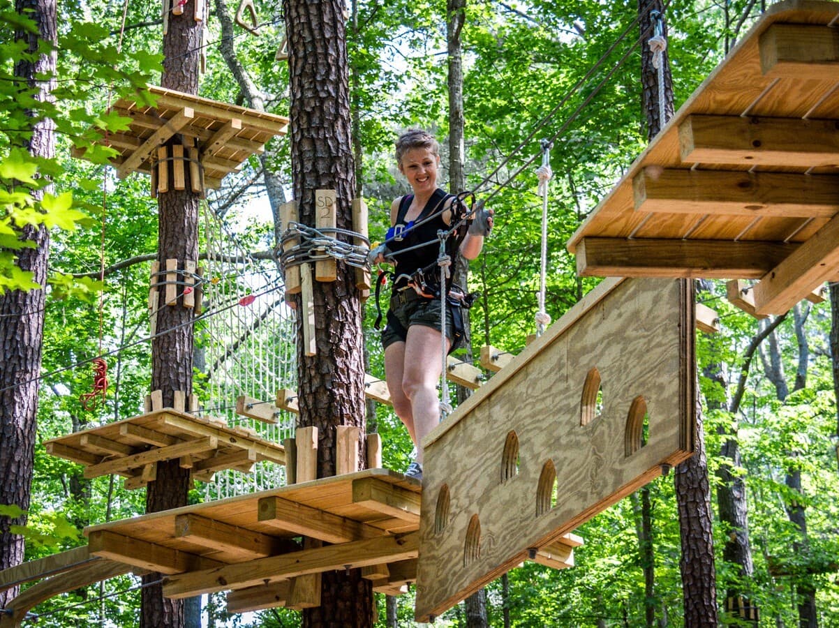 A visitor navigates the ropes course in the trees at the Adventure Park.
