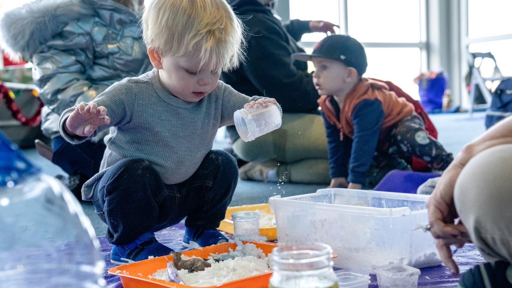 Toddler boy playing with foam from cup in toddler science program