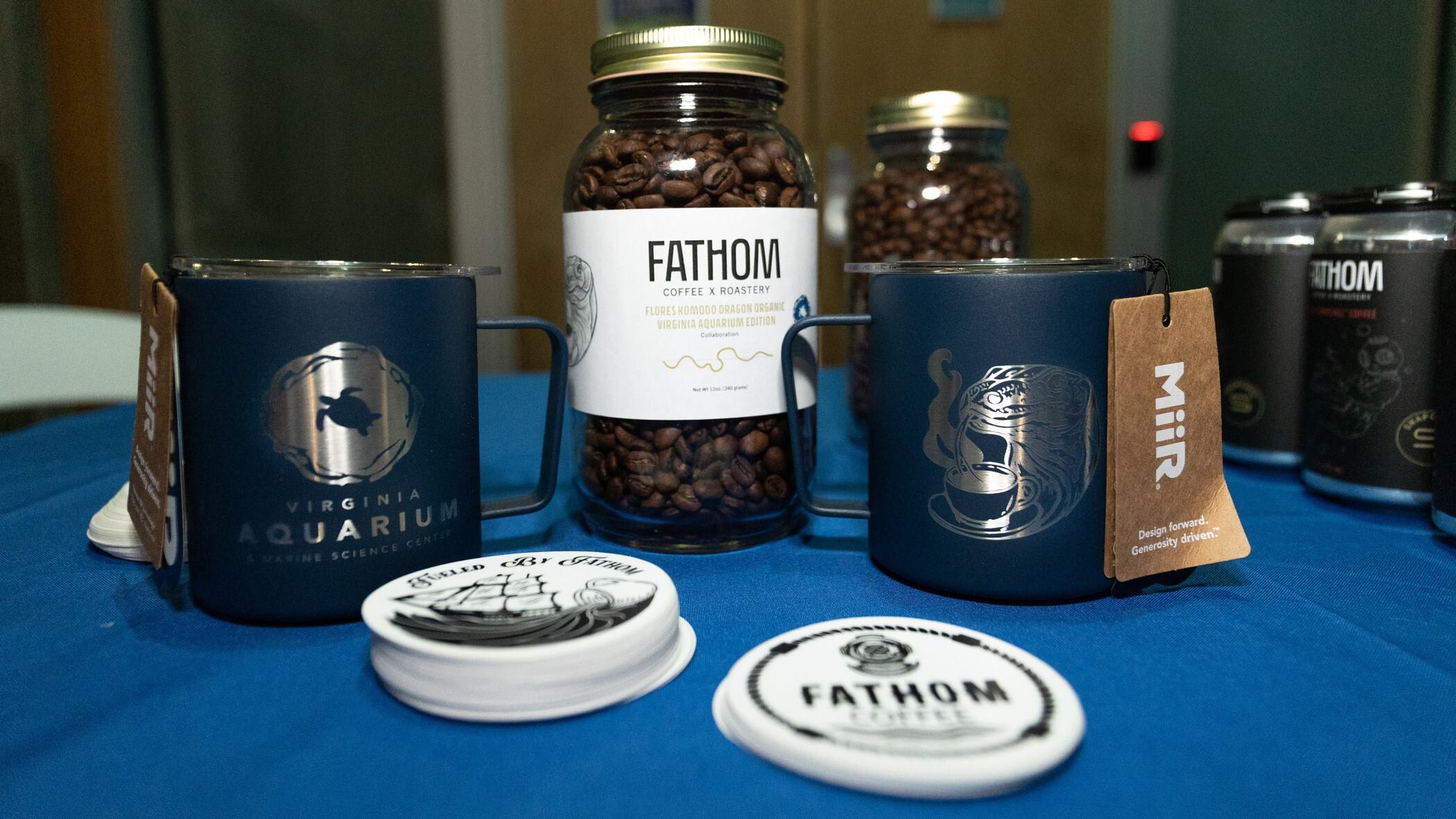 Jar of Fathom Coffee's Komodo Dragon blend alongside merchandise mugs and stickers.